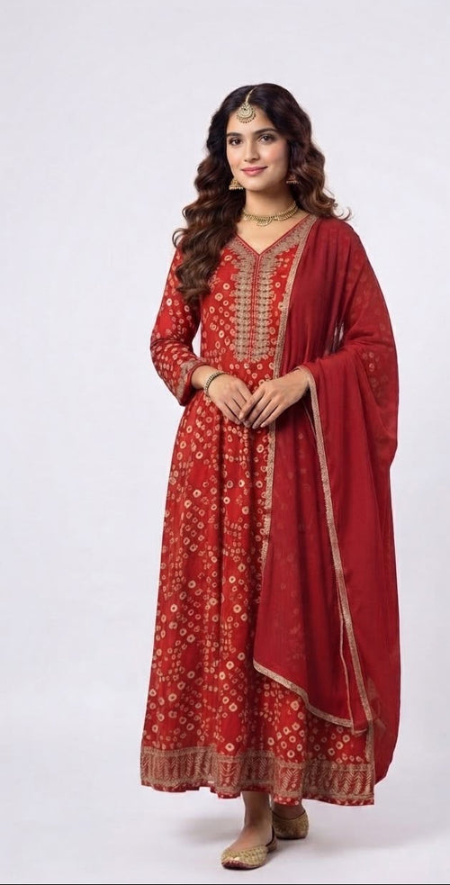A woman modeling a traditional red Indian salwar kameez suit with gold embroidery and a matching red dupatta, set against a plain light gray background.